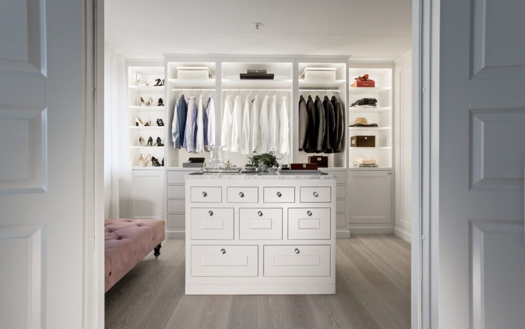 En vit walk in closet med en rosa soffa.